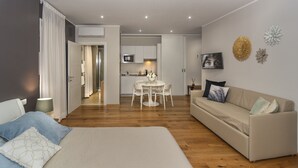 A modern living room with a sofa, a dining table, and a kitchen in the background. - Le Dimore del Borgo (Lucca)