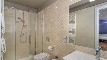 Un baño moderno con ducha de vidrio, inodoro blanco y lavamanos con espejo.