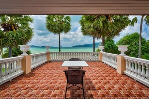 A terrace with a table and chairs, overlooking a turquoise sea and palm trees. - Fisherman Way Beach Villa (Rawai)