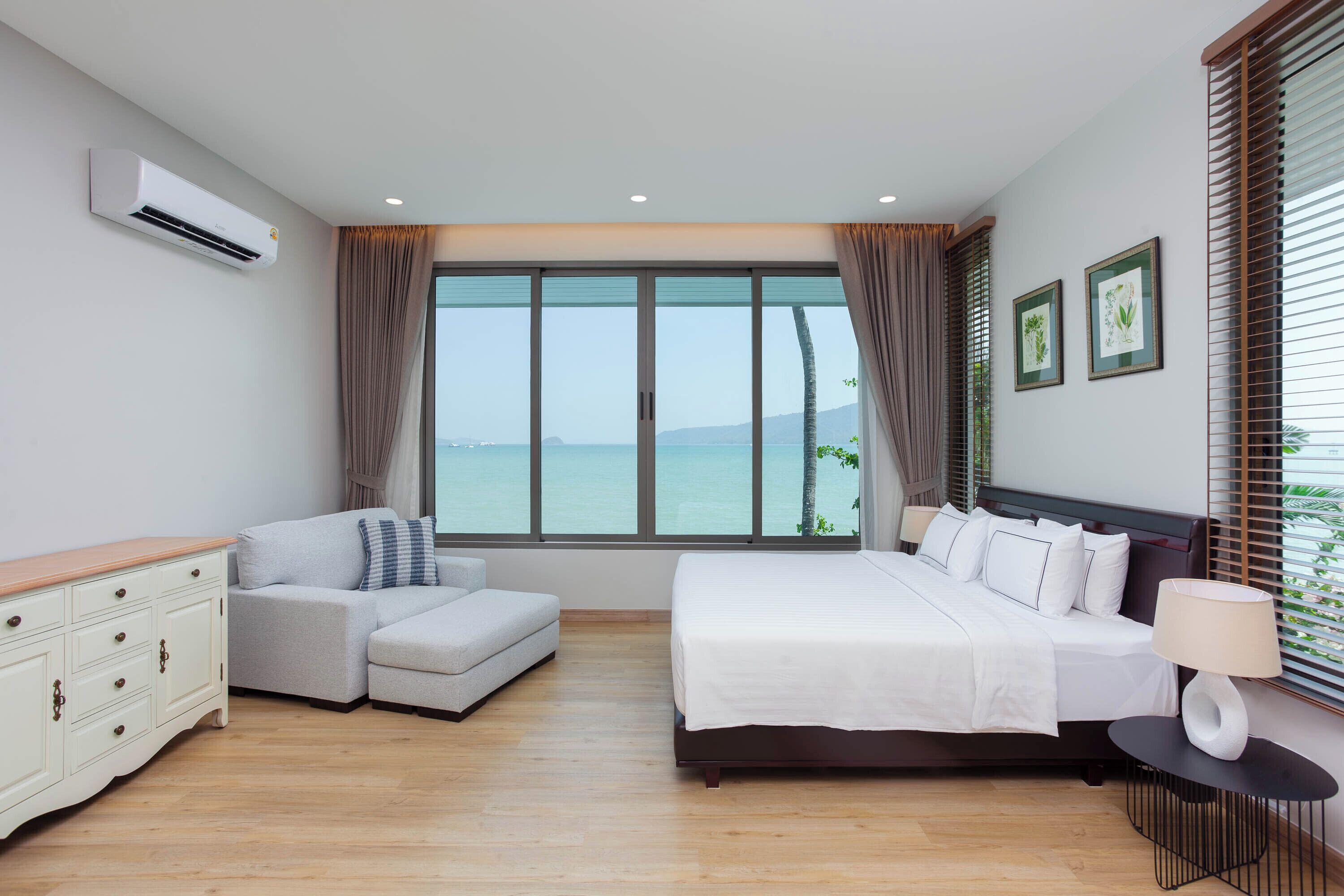 Un dormitorio moderno con un ventanal grande, una cama, un sofá y un aparador.
