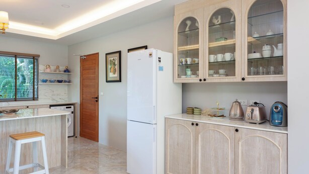 A kitchen with a white refrigerator, wooden cabinets, and a marble countertop. - Fisherman Way Beach Villa (Rawai)