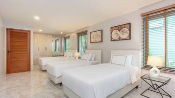 Une chambre d’hôtel avec trois lits, une porte en bois, un sol en marbre et des œuvres d’art accrochées aux murs.