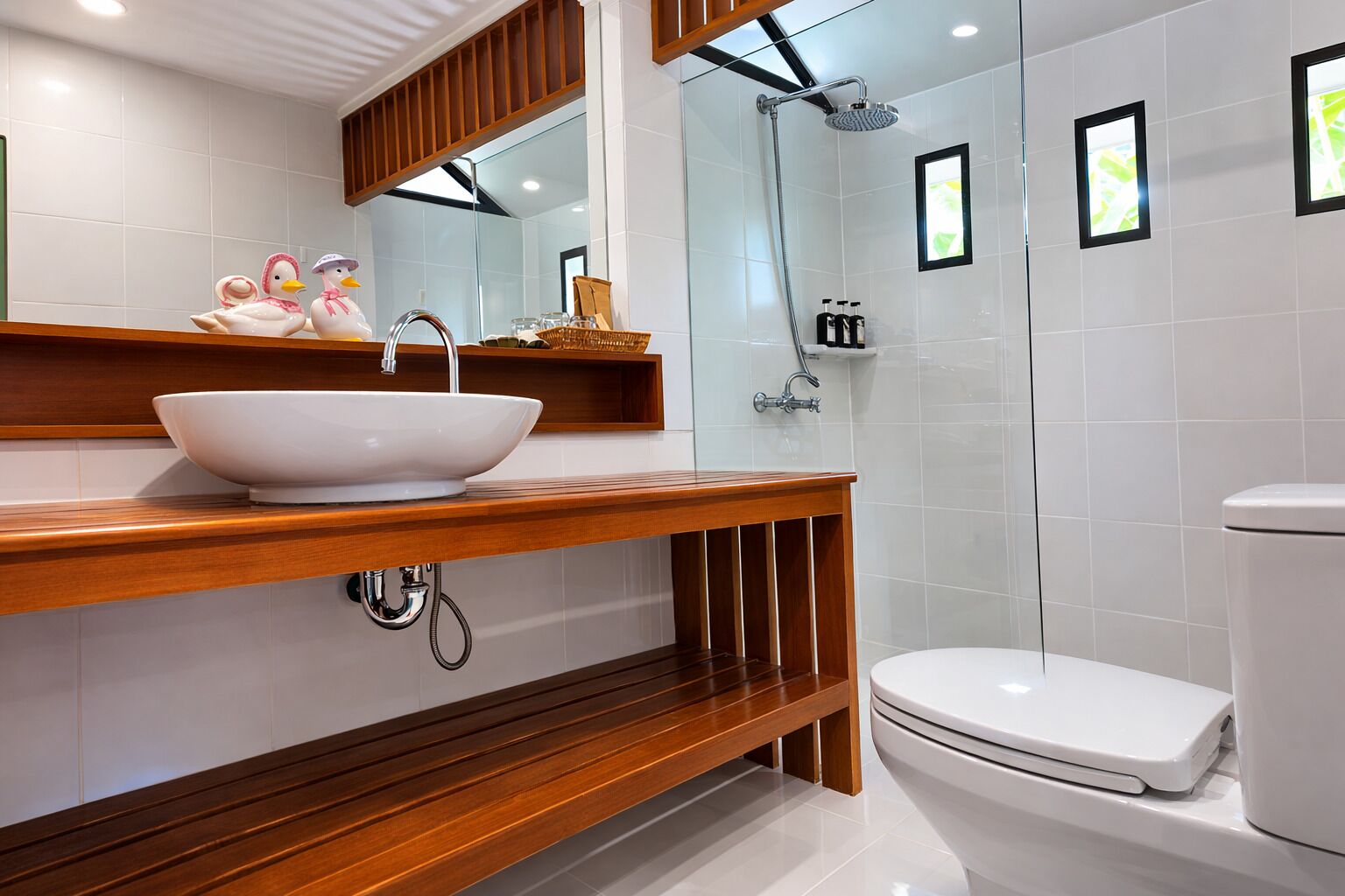 A modern bathroom with a wooden vanity, a white sink, a glass shower enclosure, and a toilet.