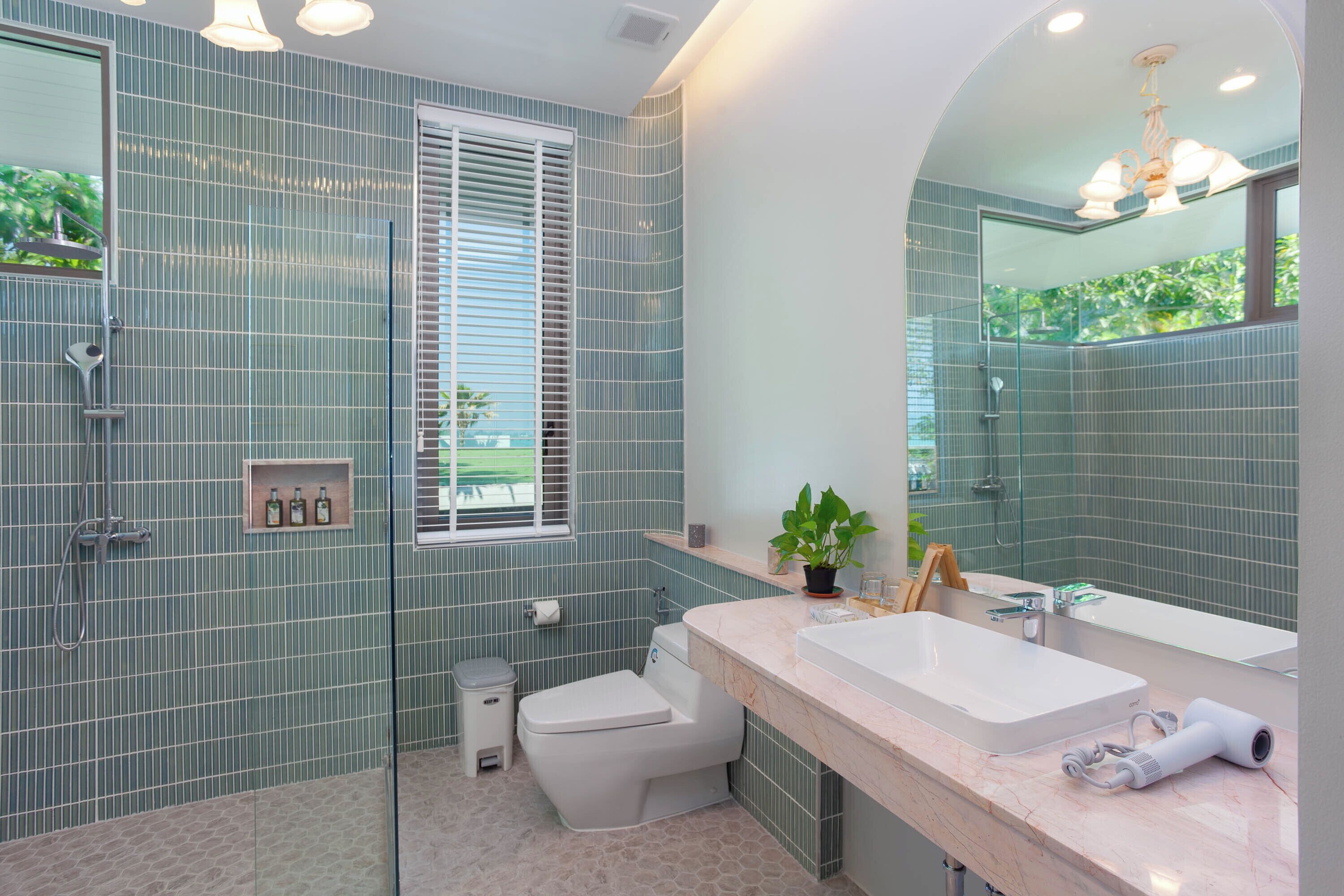 Une salle de bain avec un grand miroir, deux lavabos, une douche et des toilettes.