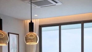 Una habitación moderna con un sofá blanco, una silla negra y un ventanal con vista al mar.
