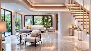 Un amplio salón con techo alto, una escalera y un ventanal con vistas a zonas verdes.