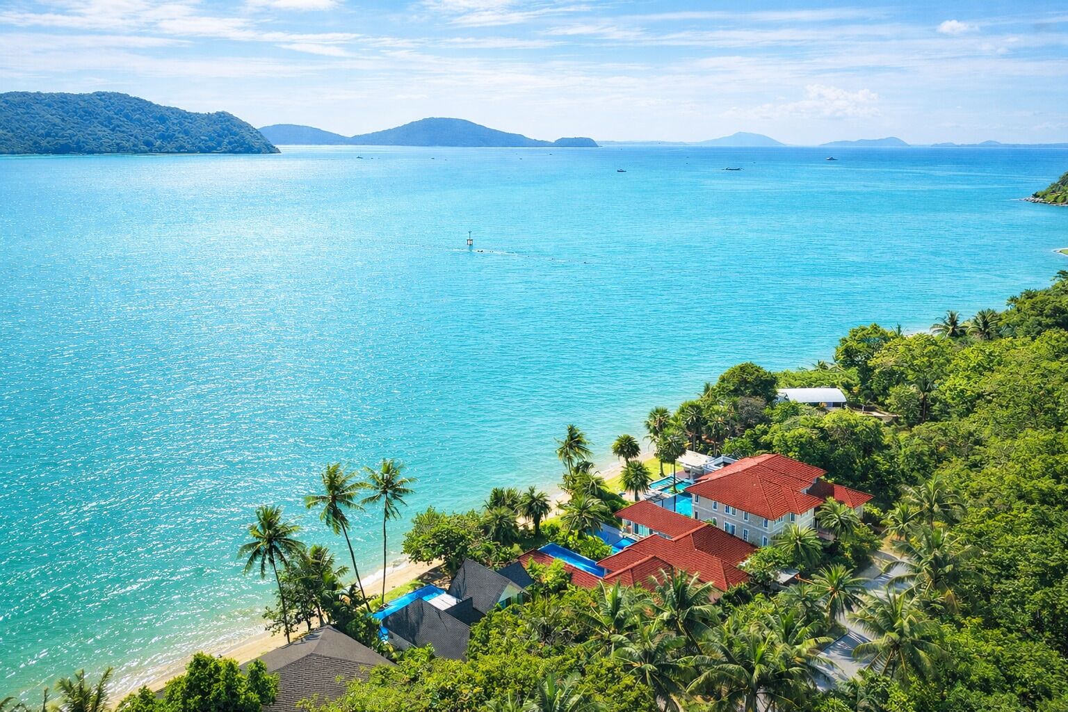 A coastal property with a pool, beach access, and lush greenery.