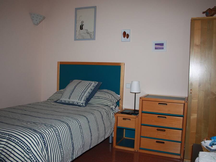 Un dormitorio con cama, mesita de noche, lámpara y un armario de madera.