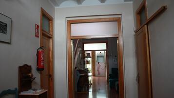 Un pasillo con puertas de madera, un extintor y un cuadro en la pared.