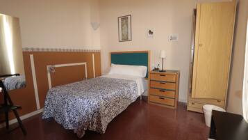 Een slaapkamer met een bed, nachtkastje, kledingkast en een stoel.