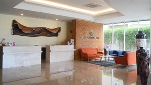 A hotel reception area with a reception desk, a sofa, and a large vase. - Grand Orchid Hotel Yogyakarta (Depok)