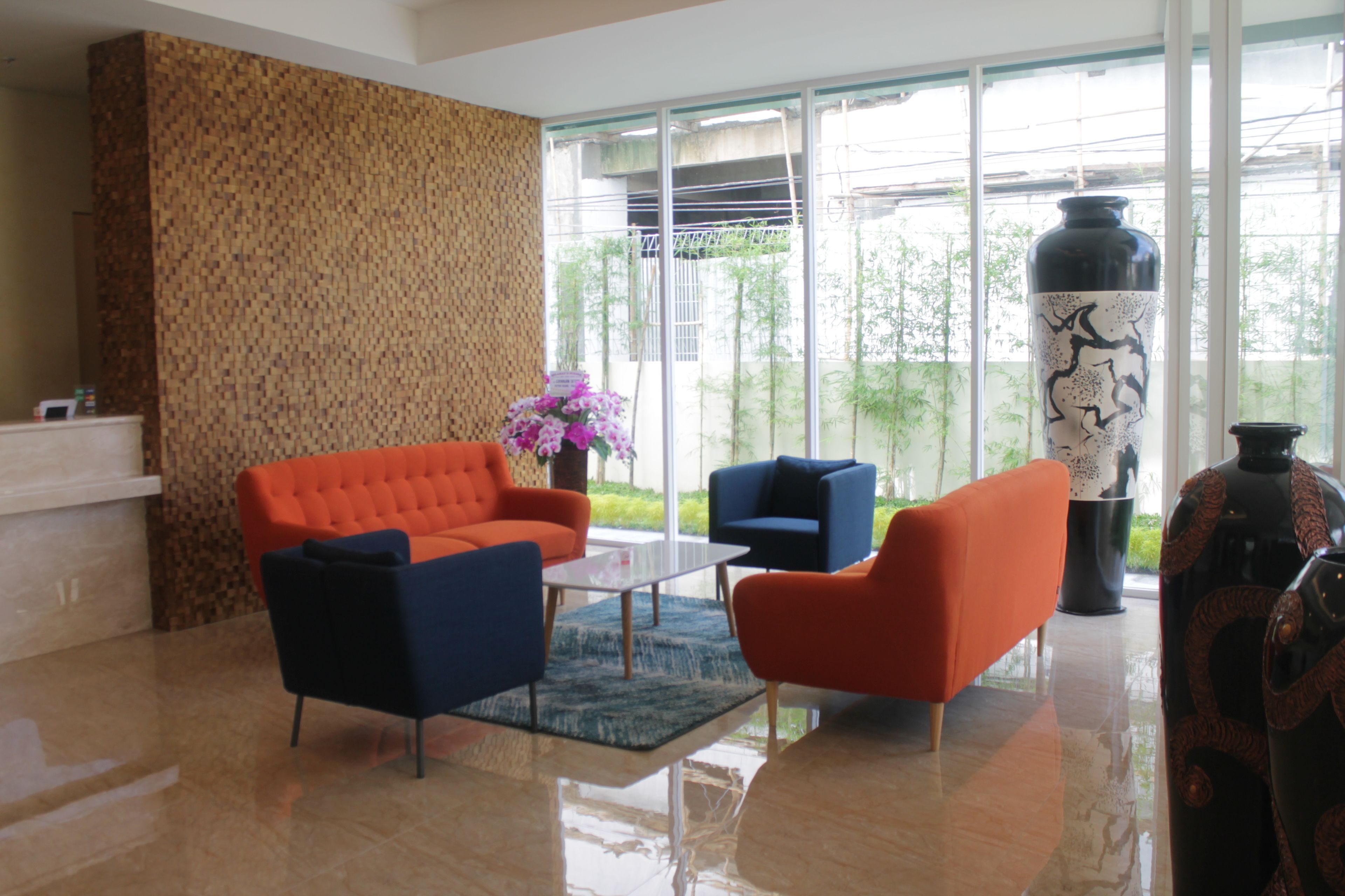 Een moderne woonkamer met een groot raam, een behang met patroon, en een combinatie van oranje en blauwe meubels.