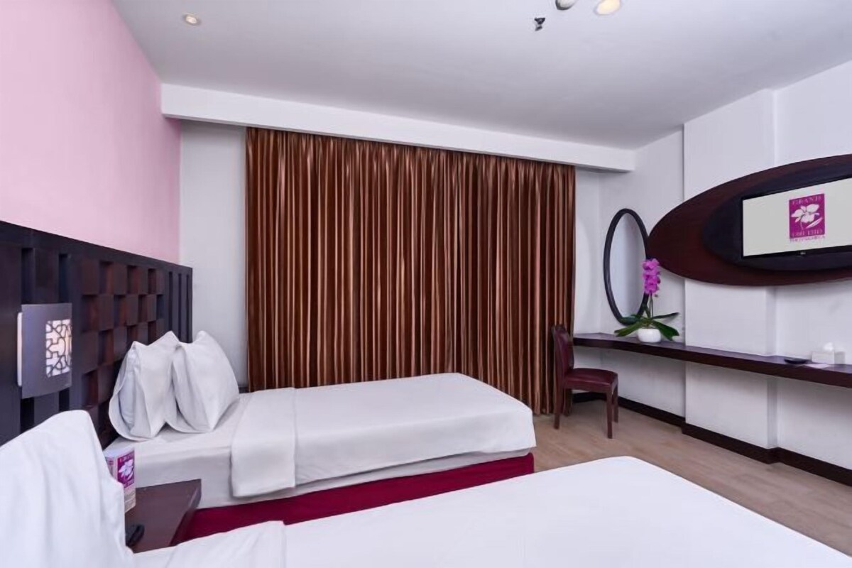 Ein Hotelzimmer mit zwei Betten, einem Schreibtisch, einem Stuhl, einem großen Spiegel und einer dekorativen Wandverkleidung.