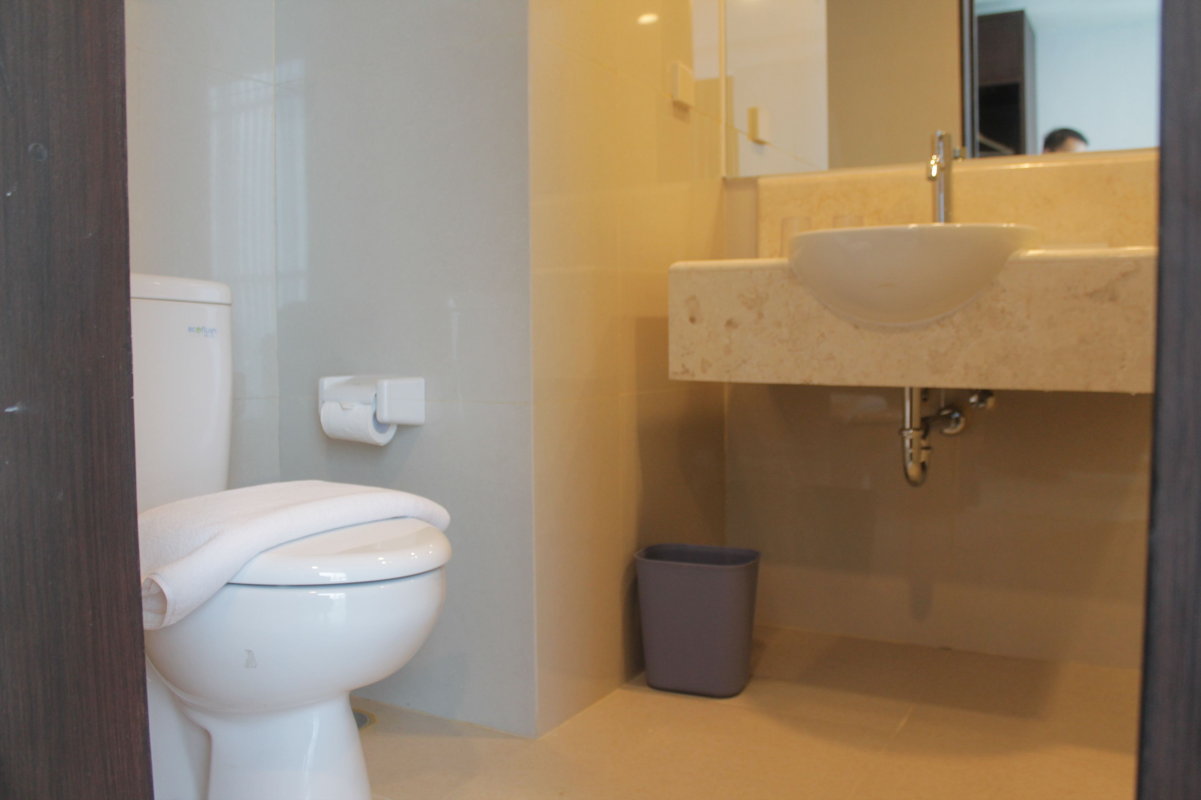 A bathroom with a toilet, sink, and trash bin.