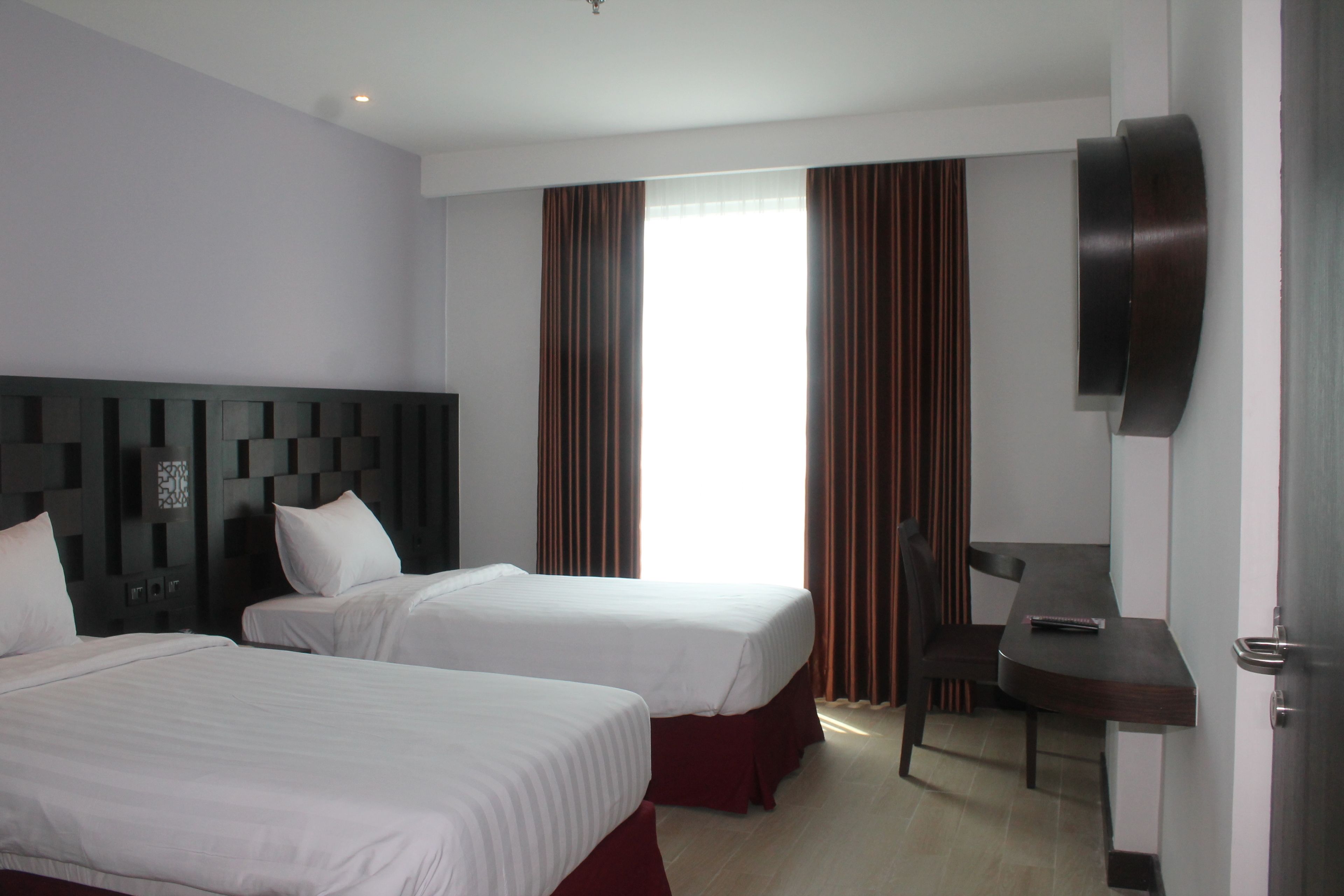 Une chambre d’hôtel avec deux lits, un bureau, une chaise et un téléviseur.