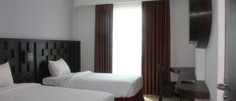 Une chambre d’hôtel avec deux lits, un bureau, une chaise et un téléviseur.