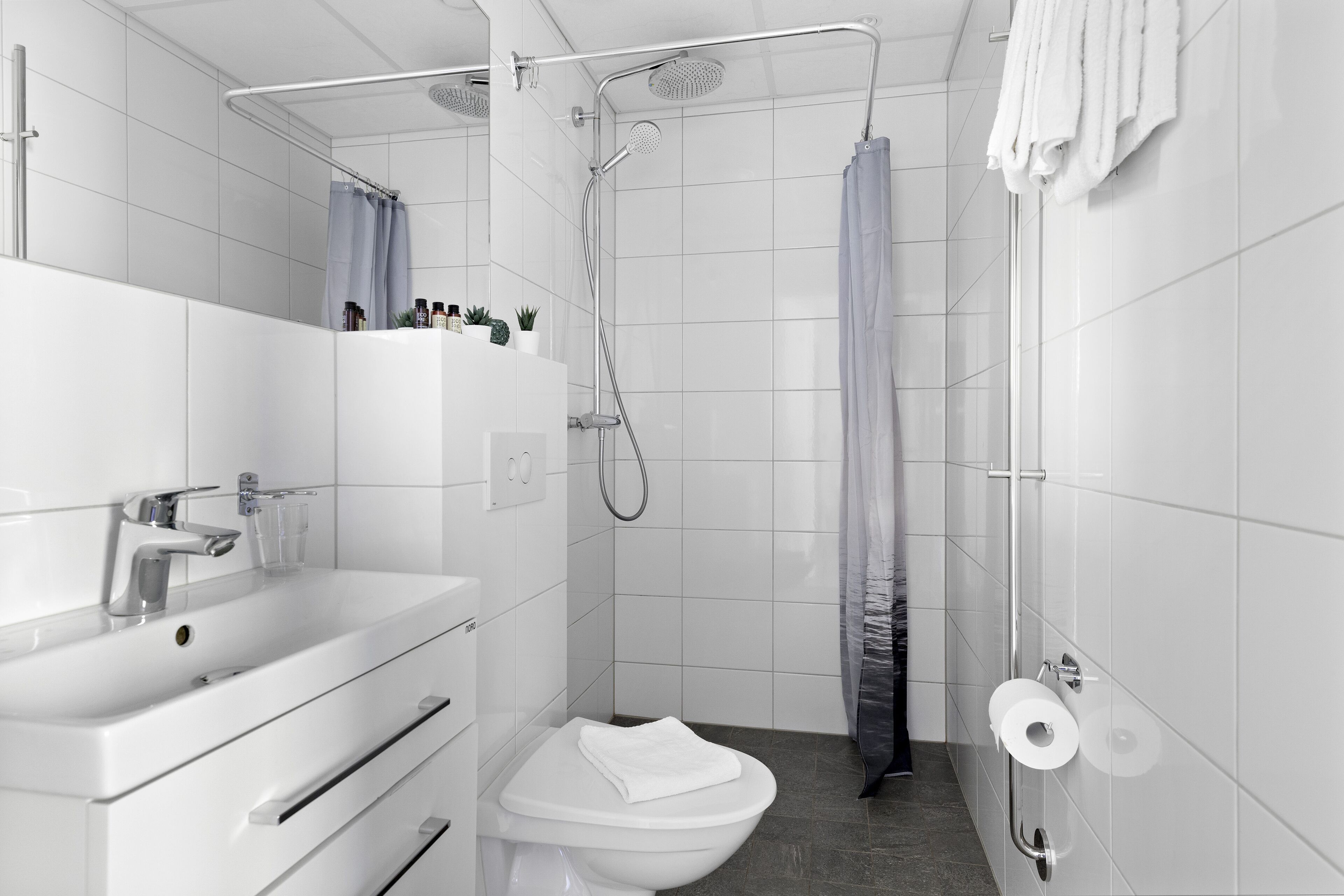 Un baño moderno con lavamanos, inodoro y ducha blancos.