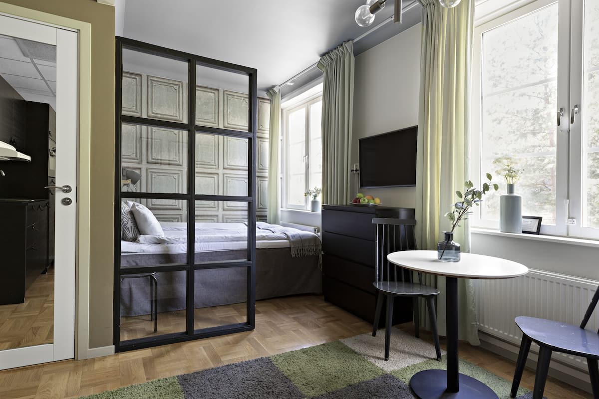 Ein modernes Schlafzimmer mit Bett, Schreibtisch, Stuhl und Fernseher.