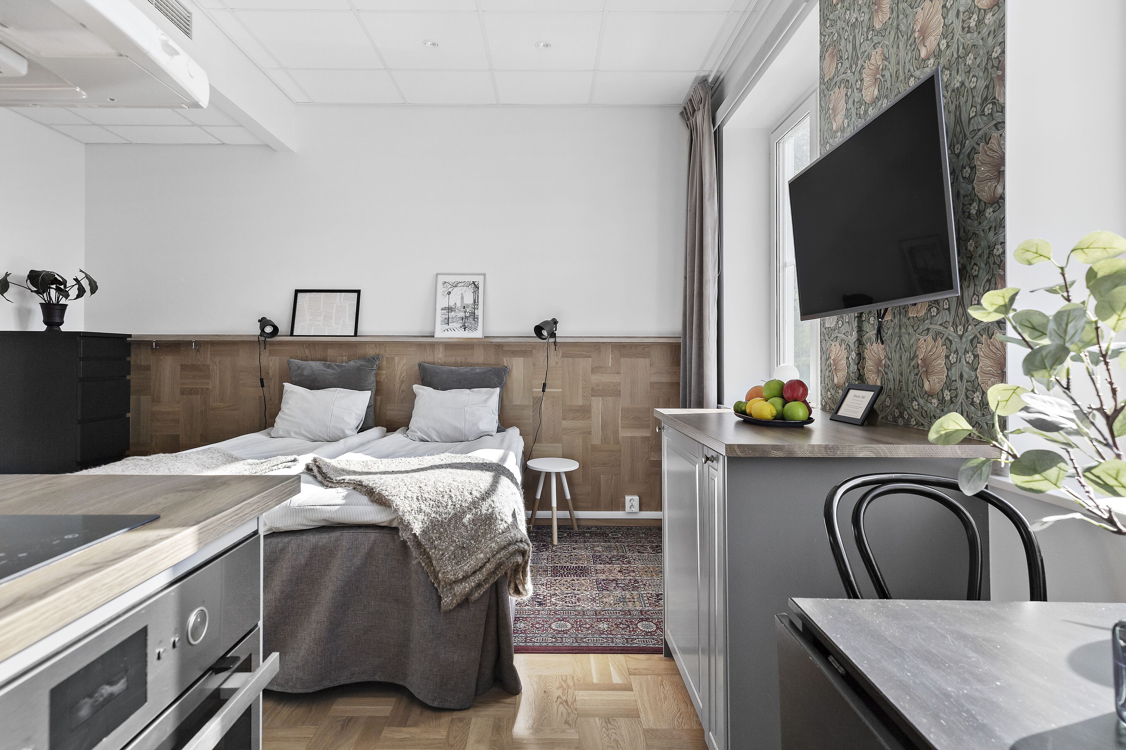 Une chambre à coucher moderne, avec un lit, des tables de chevet, un bureau et un téléviseur fixé au mur.
