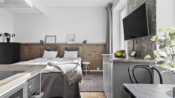 Une chambre à coucher moderne, avec un lit, des tables de chevet, un bureau et un téléviseur fixé au mur.