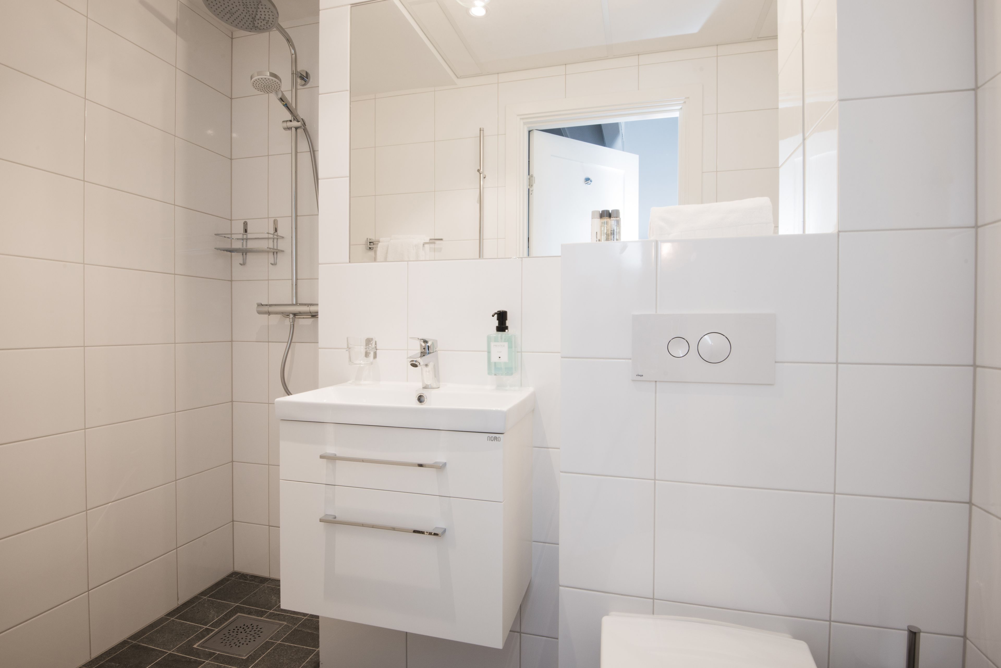 A modern bathroom with a shower, sink, and toilet.