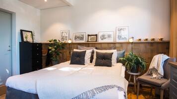 A neatly arranged bedroom with a large bed, a dresser, a chair, and a bedside table with a lamp.