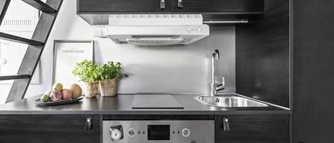 Uma cozinha moderna com armários escuros, eletrodomésticos de aço inoxidável, forno embutido e uma janela com vista.