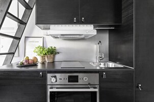 Una cocina moderna con armarios oscuros, electrodomésticos de acero inoxidable, un horno empotrado y un ventanal con vistas.