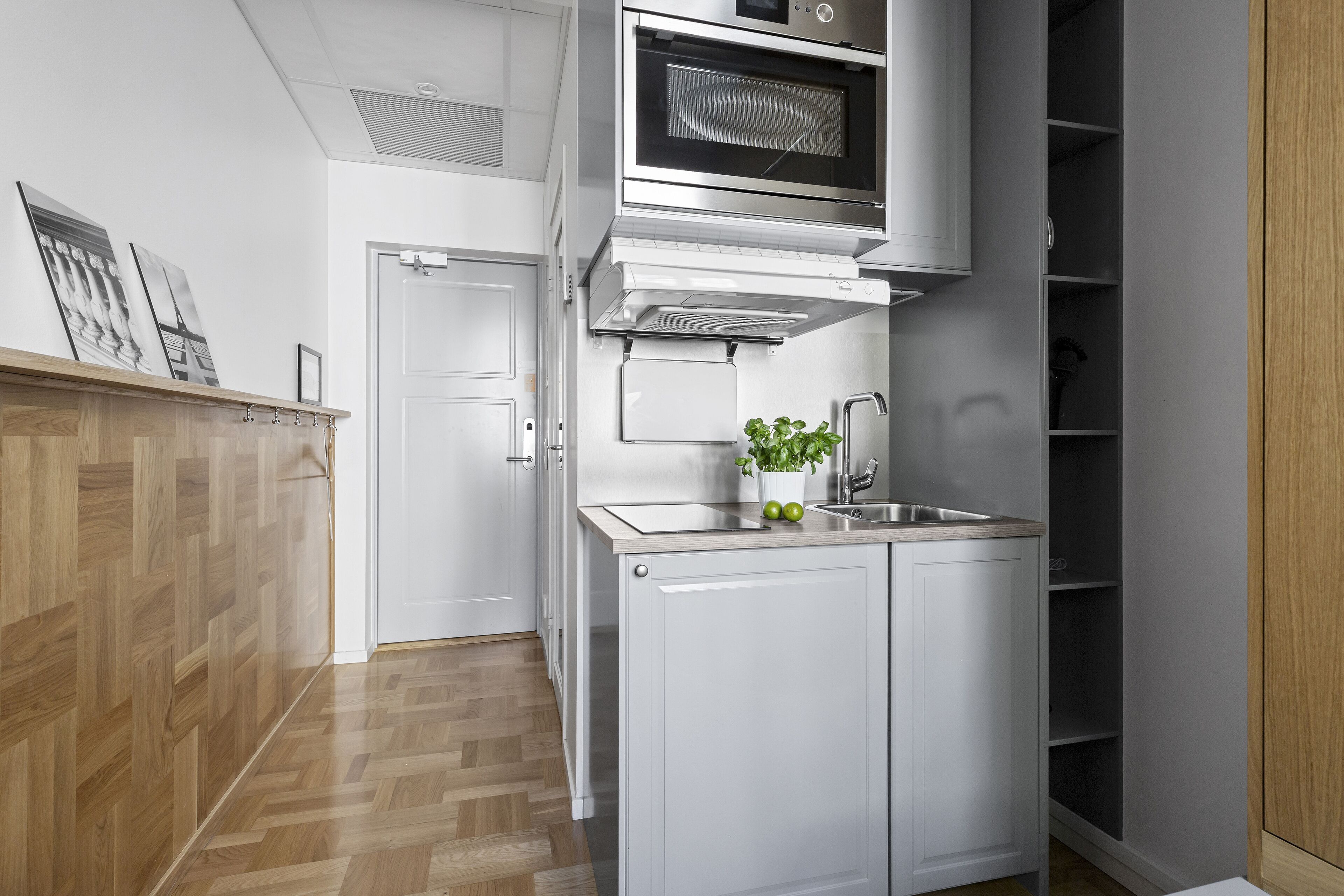 Una cocina compacta con microondas, fregadero y armarios.