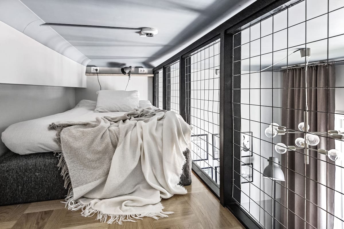 Ein modernes Schlafzimmer mit Bett, großem Fenster mit Blick und einer Deckenleuchte.