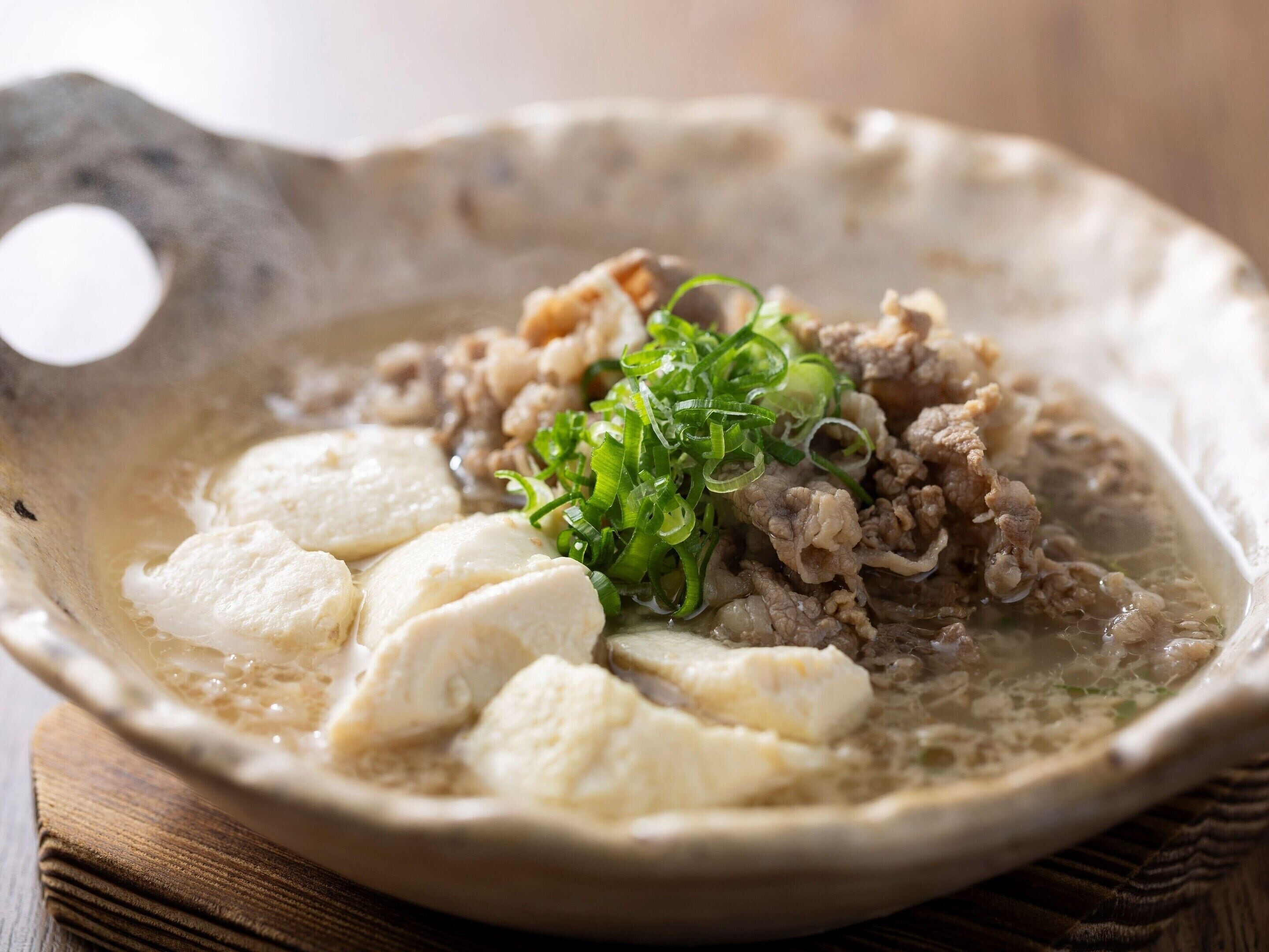 A bowl of soup with meat and green onions.