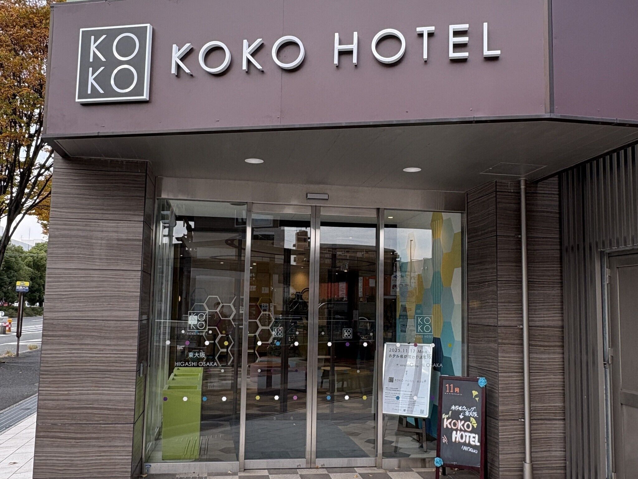 The entrance of Koko Hotel with a modern facade, glass doors, and a signboard displaying the hotel's name.