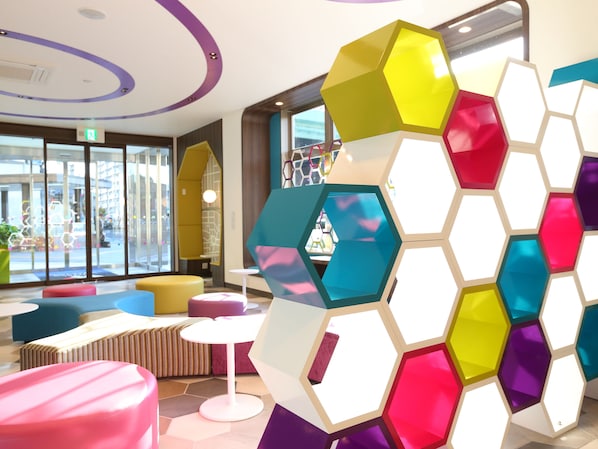 Un intérieur moderne avec des cloisons hexagonales aux couleurs vives, des sièges confortables et de grandes fenêtres donnant sur la rue.
