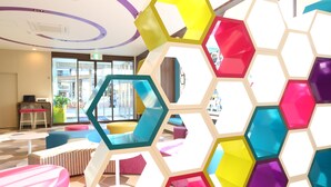 A modern interior with colorful hexagonal partitions, seating areas, and a reception desk. - KOKO HOTEL Higashiosaka (Higashi-osaka)