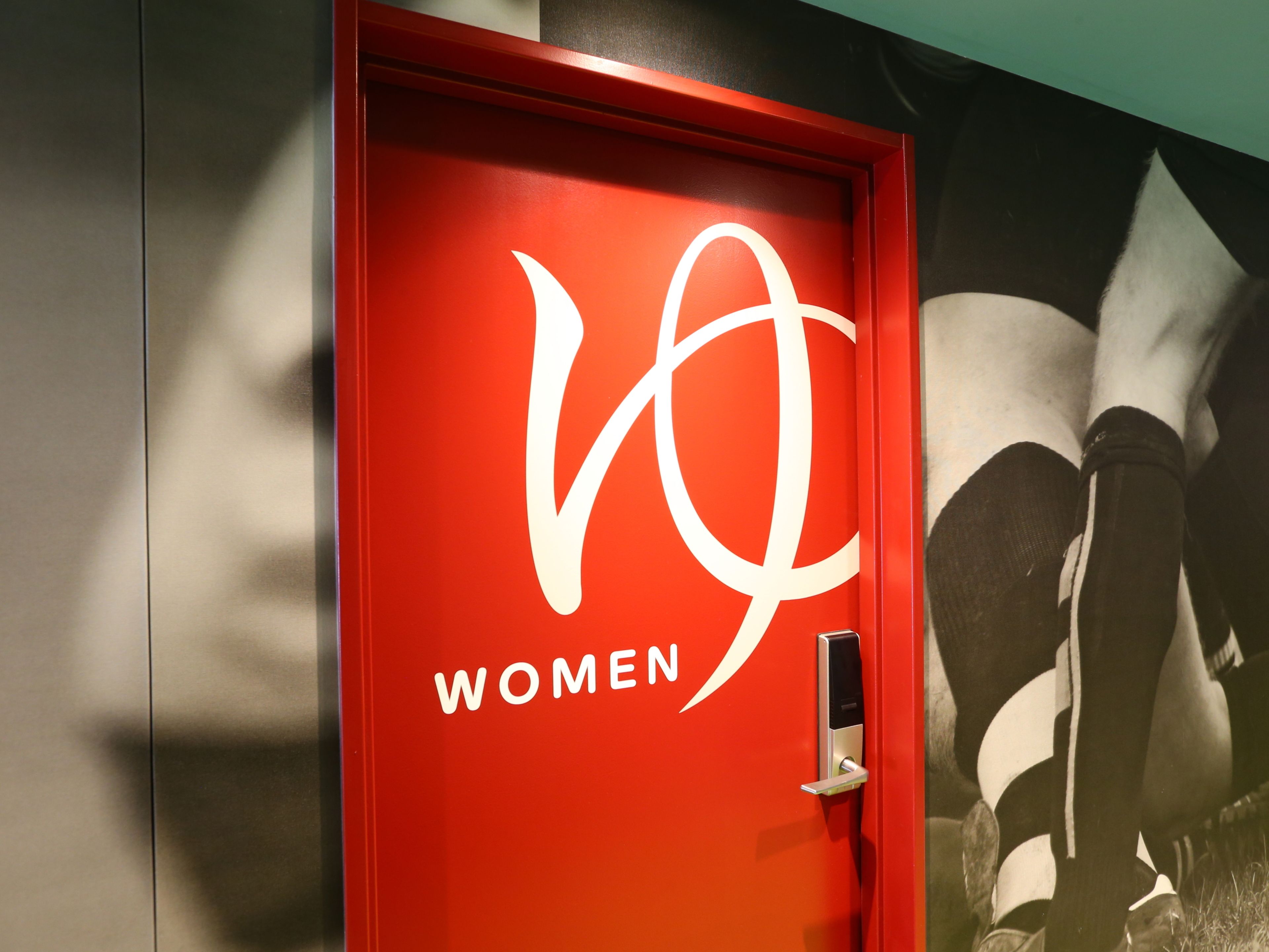 A red door with a logo and the word "WOMEN" on it.