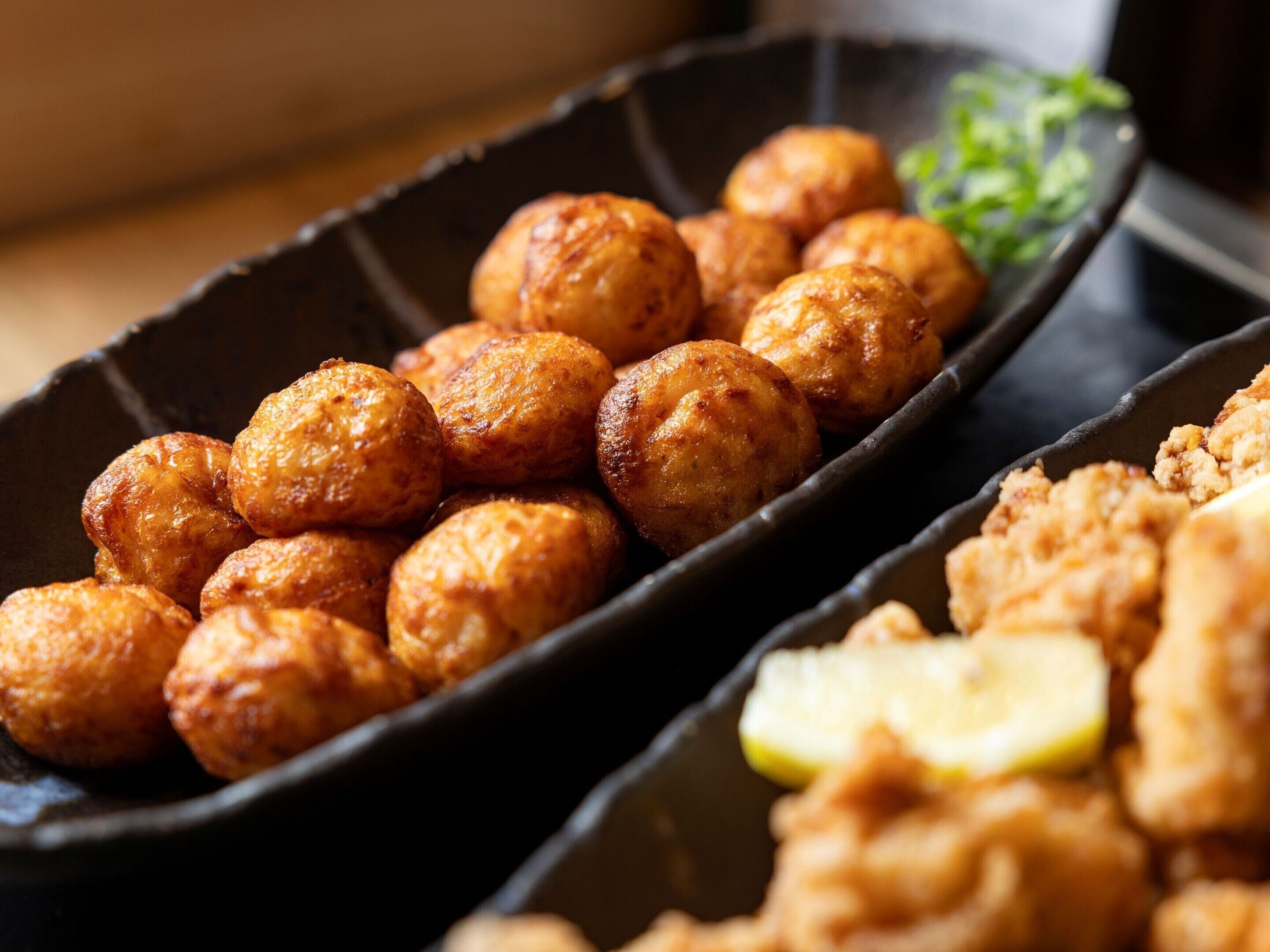 A tray of fried food items, possibly fritters, in a black serving dish.