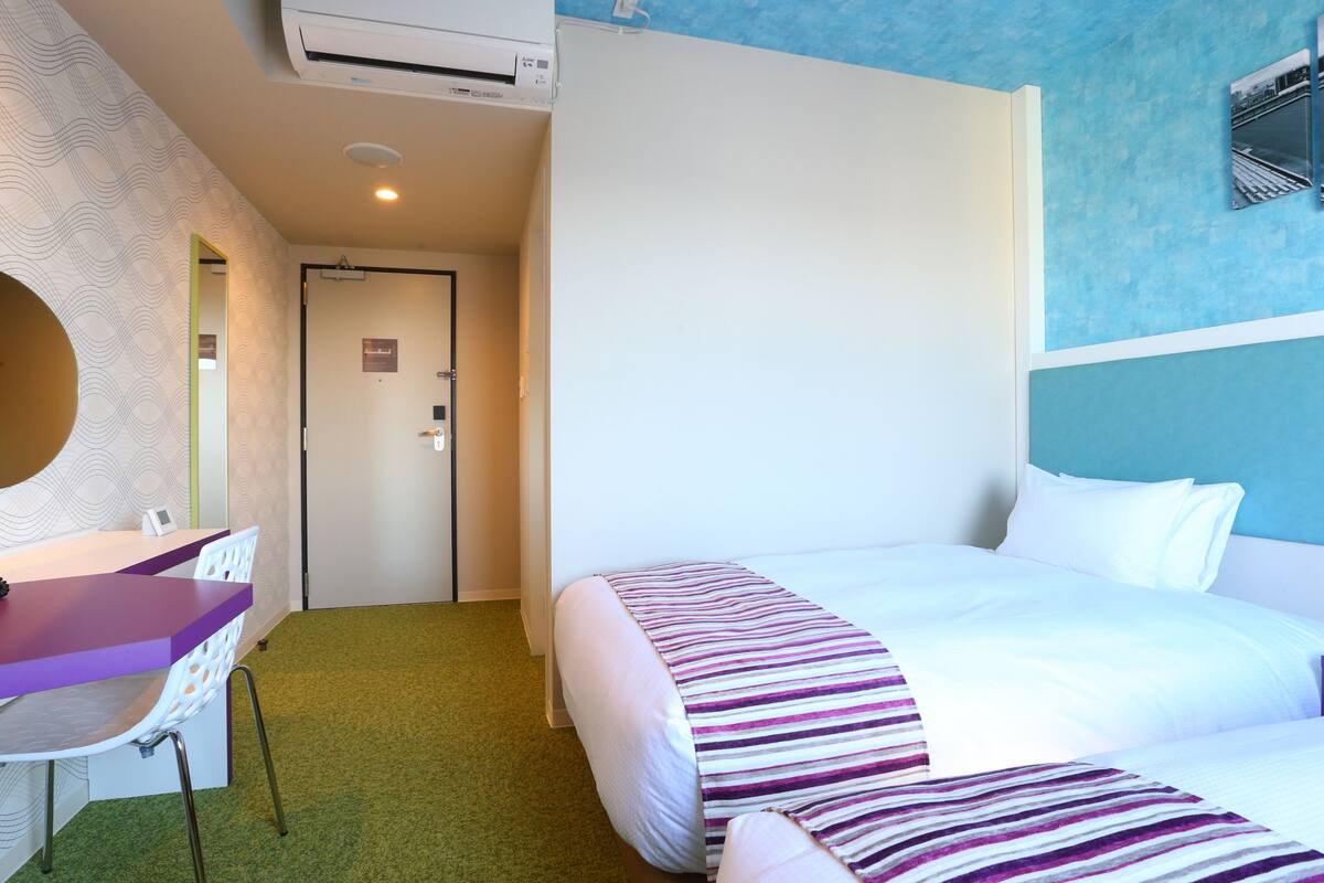 Une chambre d’hôtel avec un lit, un bureau et une chaise.