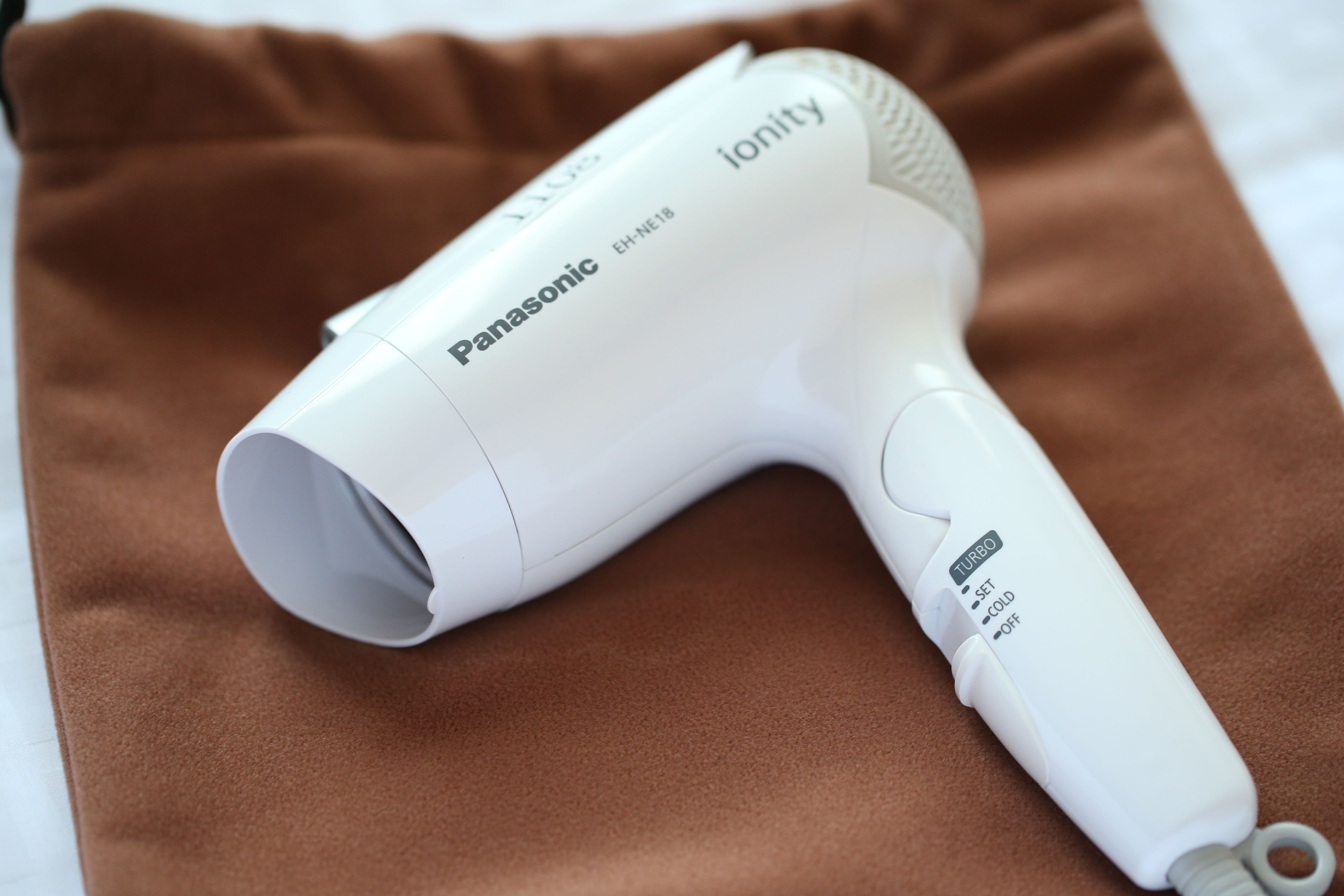 A Panasonic ionity hair dryer on a brown fabric surface.