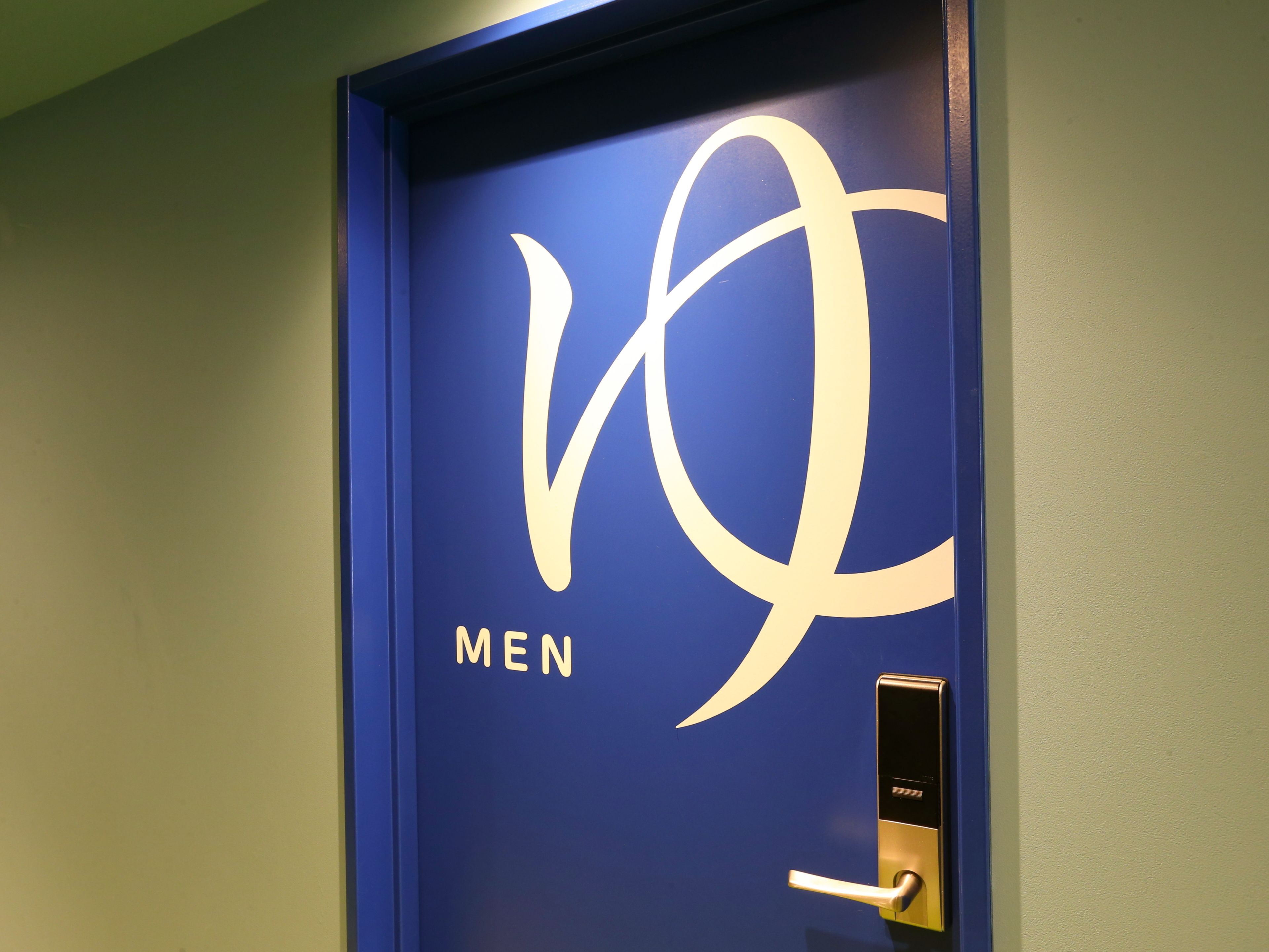 A blue door with a large white logo and the word "MEN" below it.