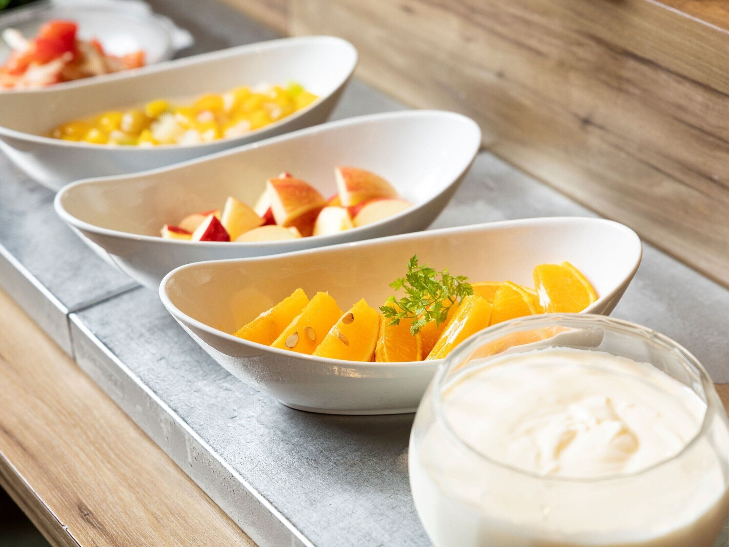 A tray with bowls of fruit and a glass of a creamy beverage.