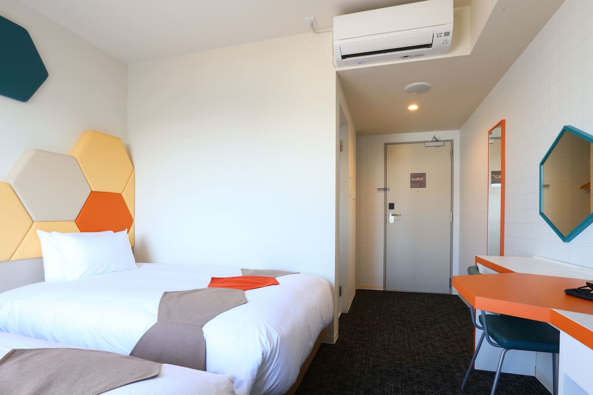 Une chambre d’hôtel avec deux lits, un bureau et une chaise.