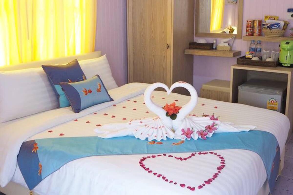 A hotel room with a bed, a wardrobe, a mirror, and a shelf with toiletries.