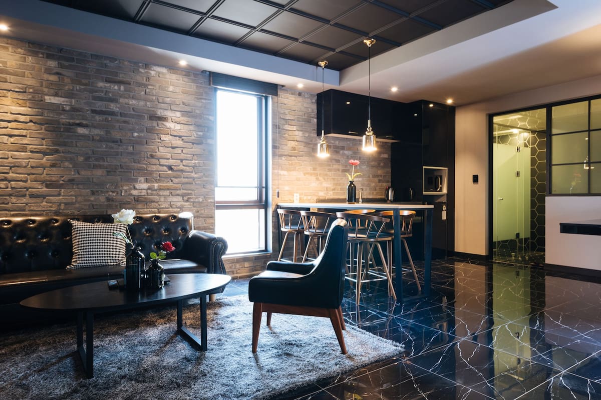 A modern living room with a leather sofa, a coffee table, and a bar area with stools.