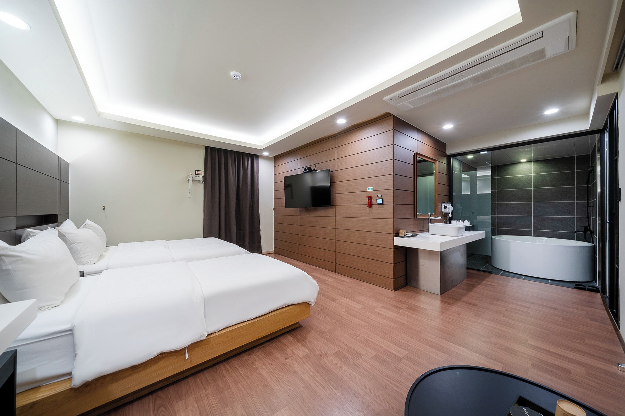A modern hotel room with a bed, a TV, a bathroom with a bathtub, and a shower.
