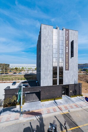 Un moderno edificio de hotel con un cartel llamativo que dice "Boutique Hotel XYZM Gran Inauguración".