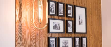 A wall with framed photographs and a hanging light fixture.