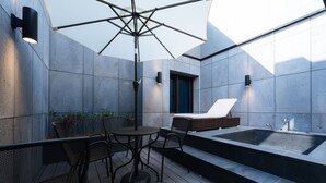 An outdoor patio with a table and chairs, a large umbrella, a built-in hot tub, and a small seating area. - Boutique Hotel XYM Pyeongtaek (Pyeongtaek)