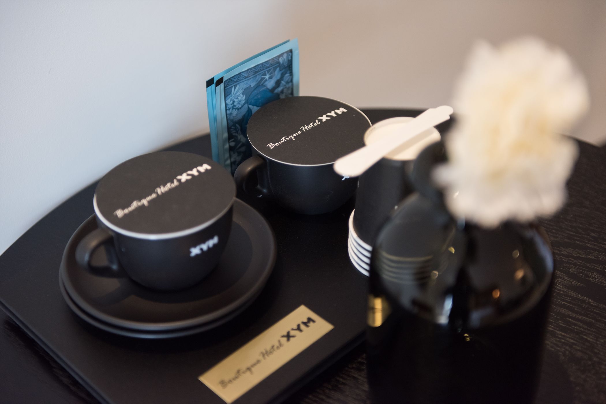 A set of black hotel branded items including a mug, a small container, and a tray with a card.