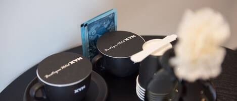 A set of black hotel branded items including a mug, a small container, and a tray with a card.