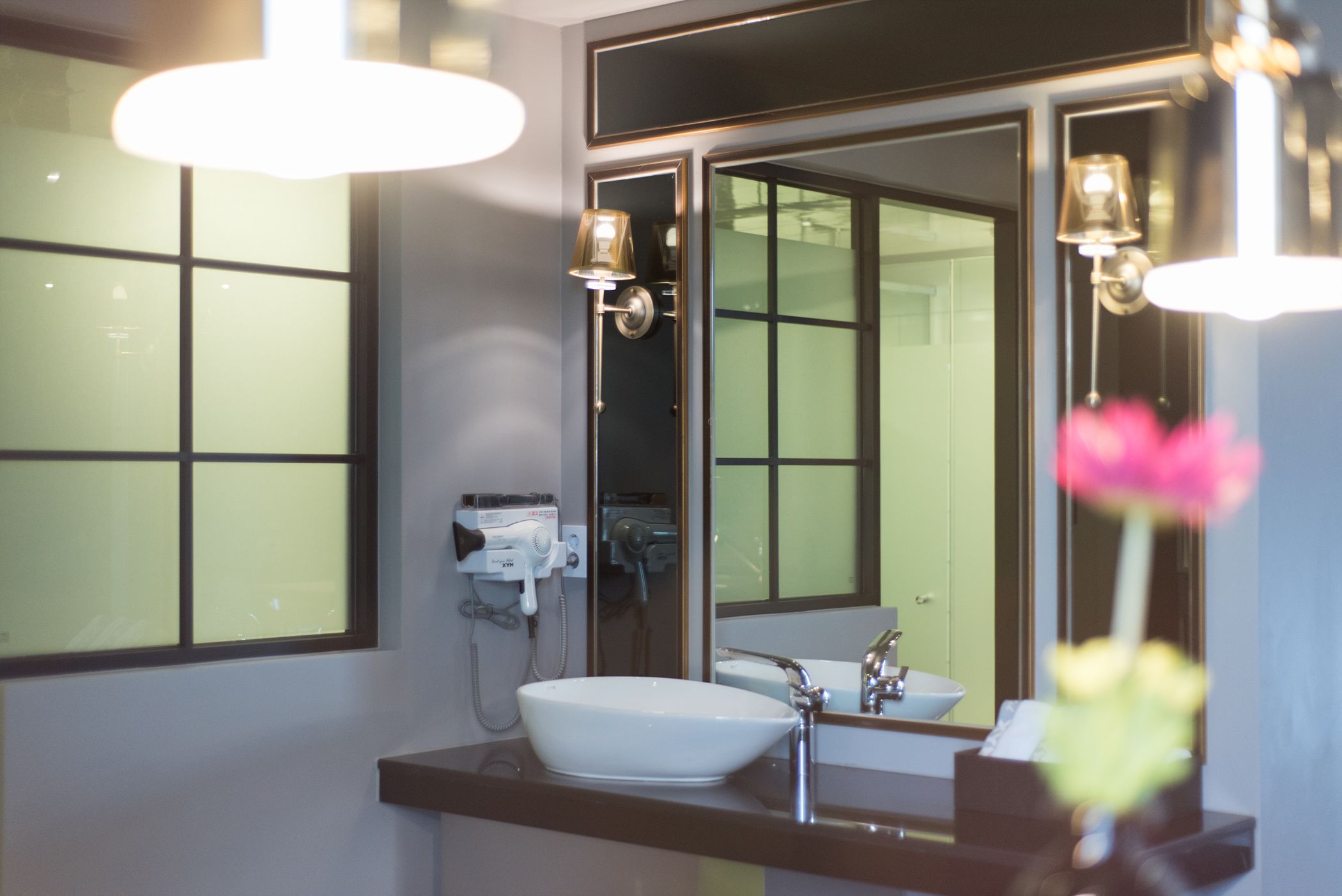 A bathroom with a large mirror, a white sink, and a handheld showerhead.